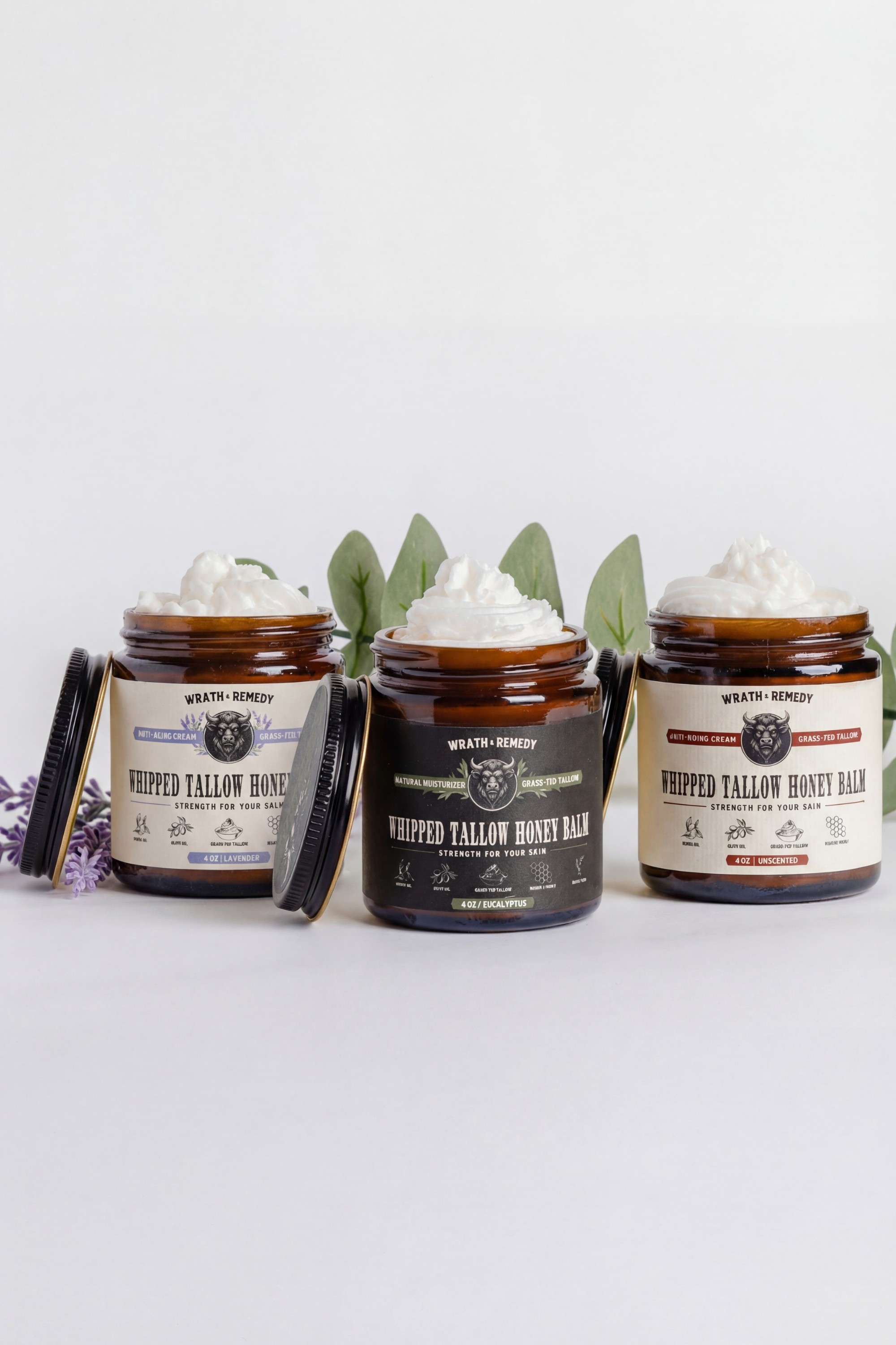 Three jars of Whipped Yellow Honey Balm on a white background with green leaves.